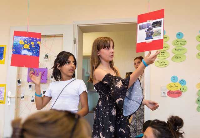 Zwei Kinder halten Karten in einem Raum.